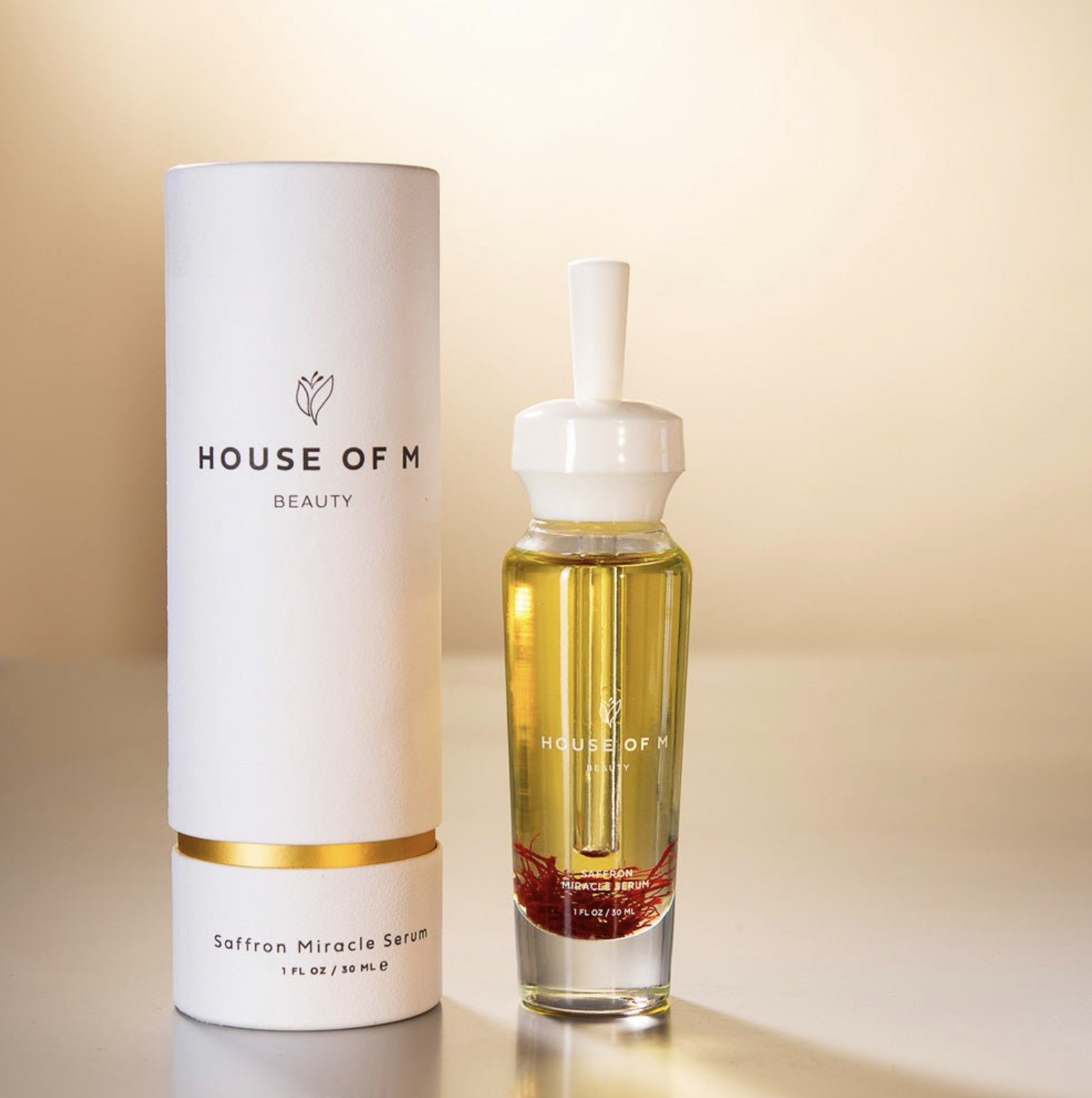 White skincare bottle and glass facial serum displayed against a warm beige background
