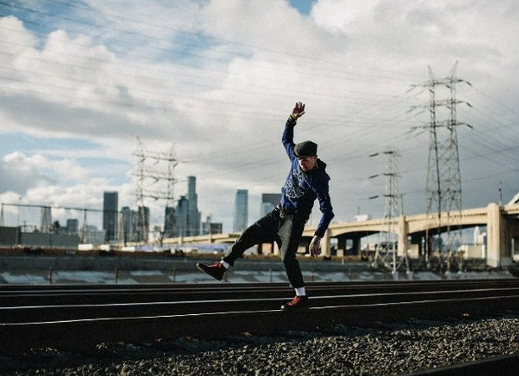 Skater mid-air at the Los Angeles rail yard with the downtown skyline behind