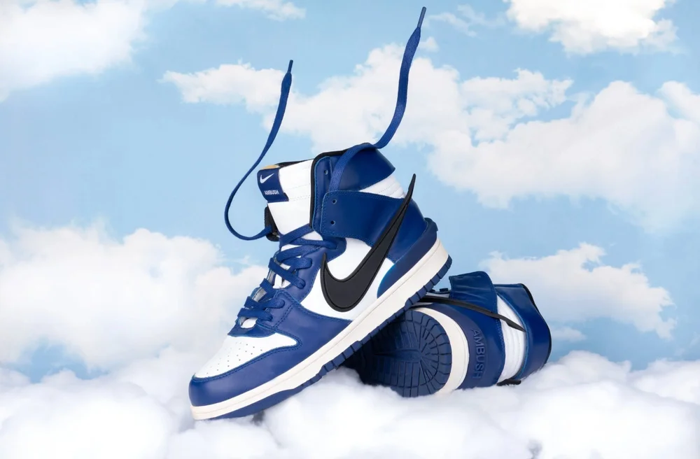Nike Air Max sneakers floating in mid-air above soft white clouds on a light blue fabric backdrop, photographed in the studio.