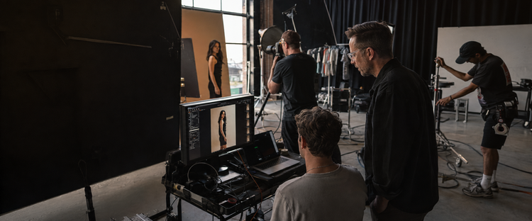 Chris Frara Studios on set for an agency lifestyle campaign in Los Angeles, photographing a model against a sculptural concrete backdrop in natural window light while the creative director reviews tethered captures live