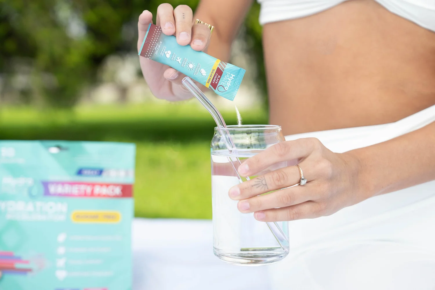 Product lifestyle photography shot on location in natural daylight, a wellness beverage poured mid-motion during an active outdoor moment for paid social and brand campaigns