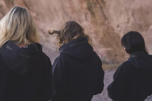 Three models from behind showing the gold Live Your Legend hood print on Women of the Galaxy hoodies