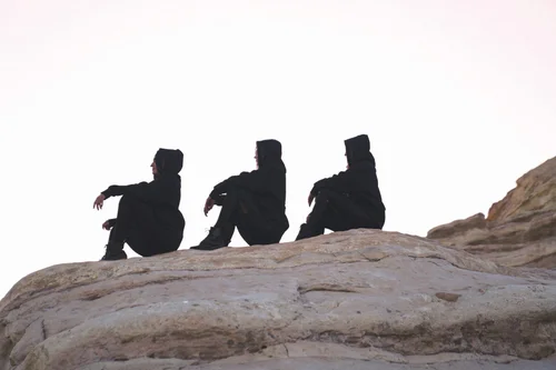 Three hooded models silhouetted on a sandstone ridge at dusk, Women of the Galaxy fall campaign