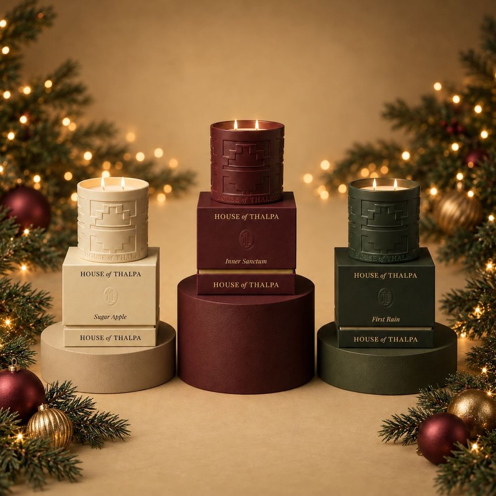 Luxury Christmas candle collection photographed as a sculptural home décor still life, with tiered gift boxes, warm directional studio lighting, controlled highlights, soft golden bokeh and evergreen styling.
