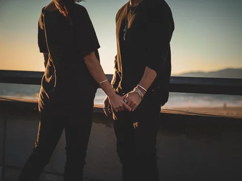 Couple holding hands by the ocean wearing Buck Palmer silver bracelets and rings, Los Angeles lifestyle jewelry campaign