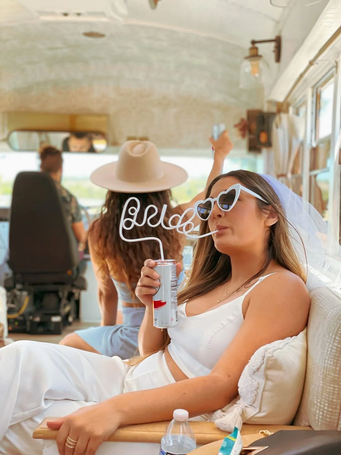 A bride in heart-shaped sunglasses celebrating with friends aboard the Toasted Tours Skoolie