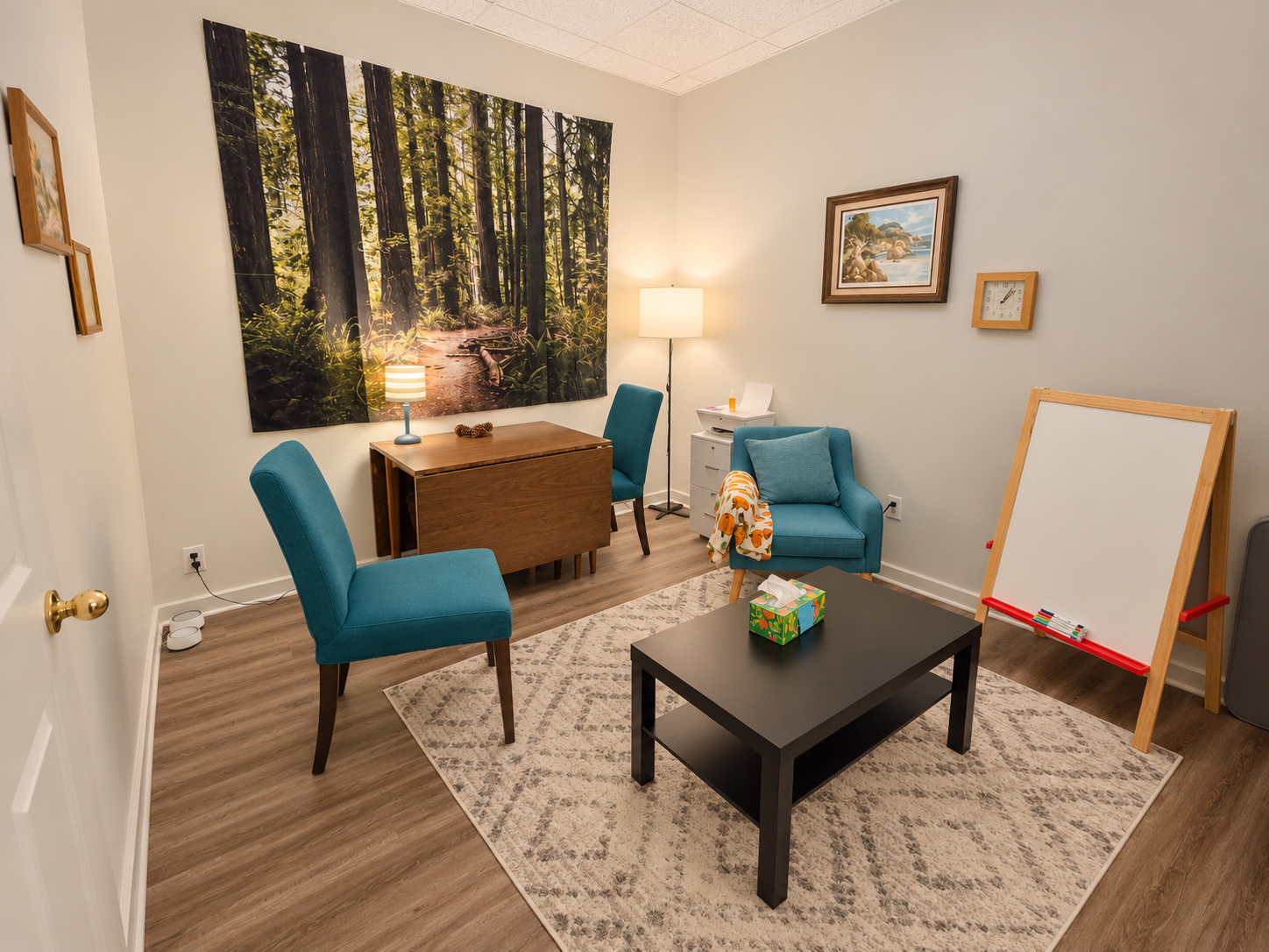 Ypsilanti therapy room with teal chairs, a woodland tapestry, lamps and a whiteboard