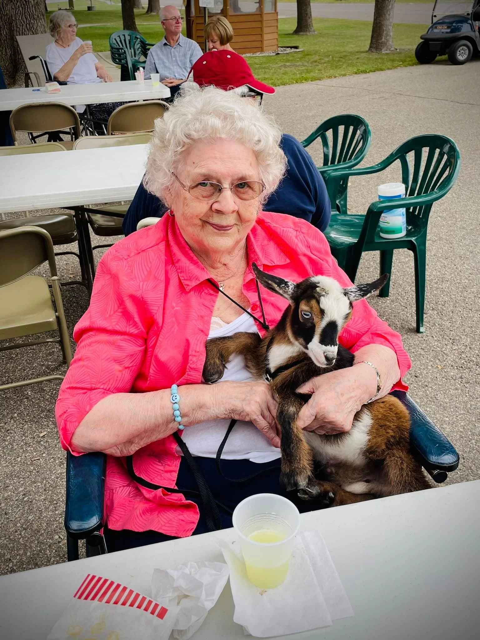 A resident enjoying a visit from one of our community's baby goats