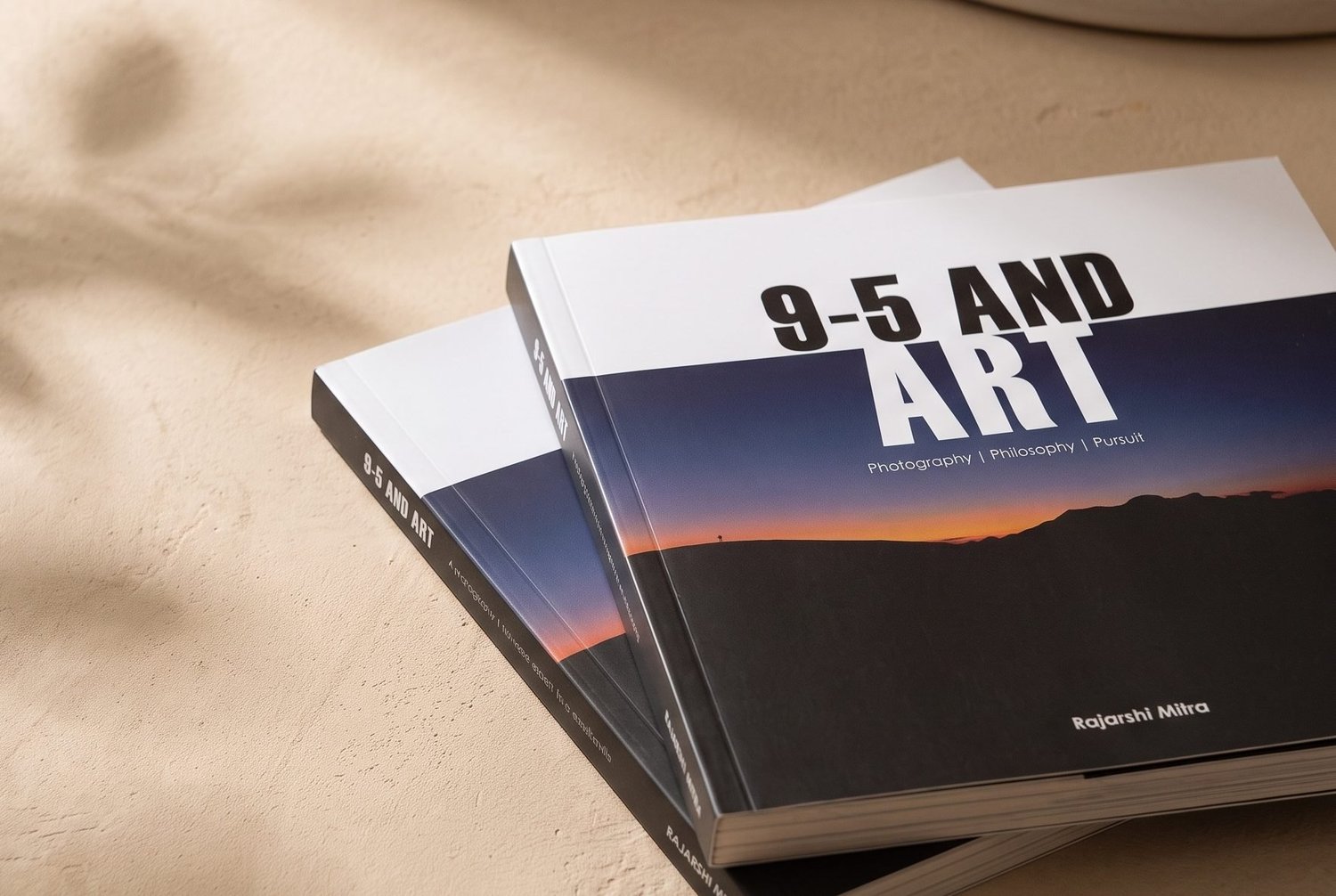 Two copies of 9-5 AND ART on a table in afternoon light