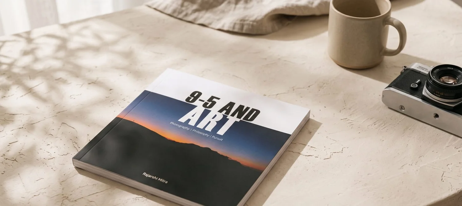 A copy of 9-5 AND ART on a stone table, next to a coffee mug and a film camera