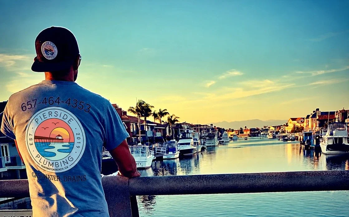 Henry Godina, founder of Pierside Plumbing, looking out over the harbor in a company shirt and hat