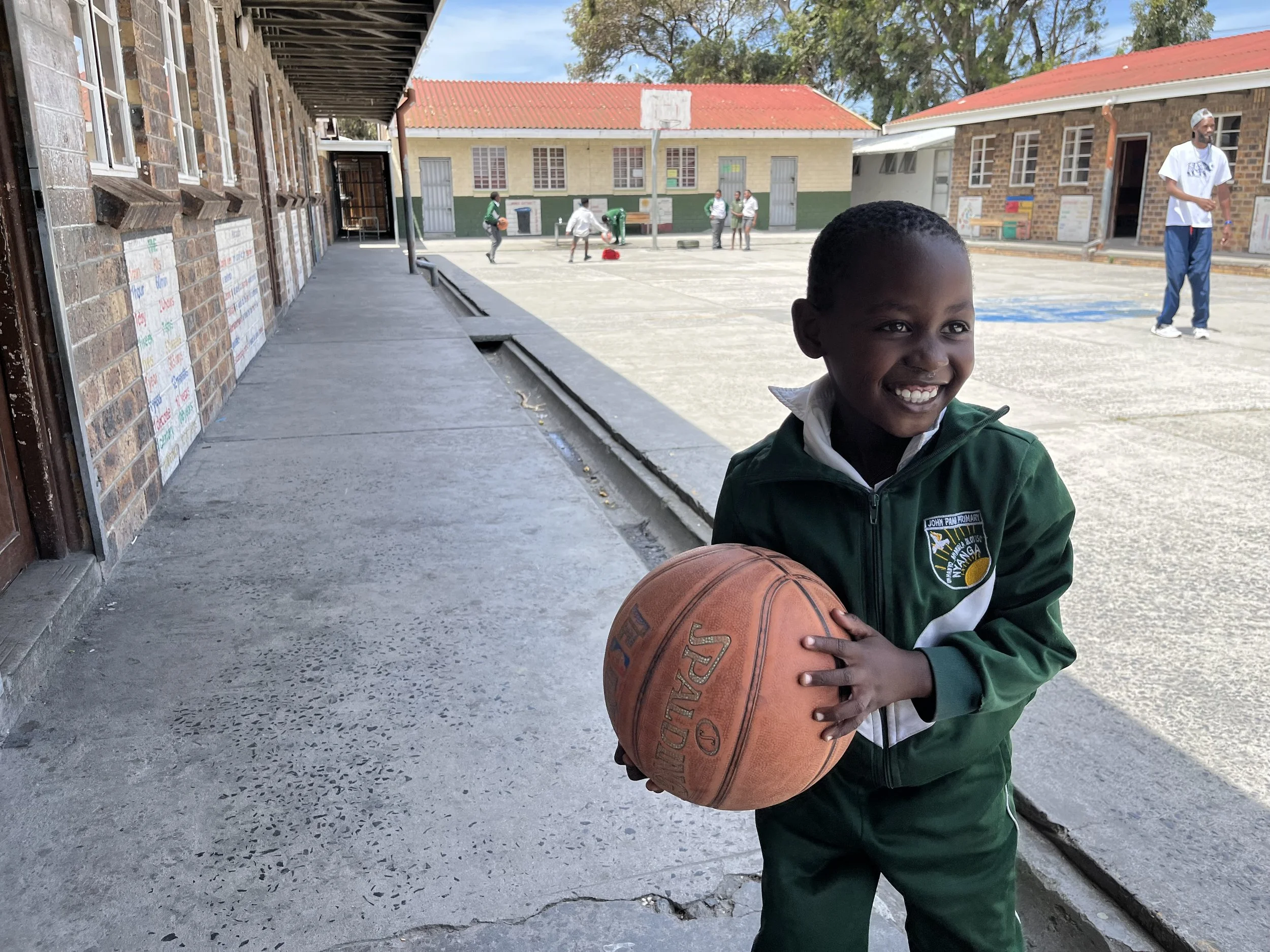 A young Hoops 4 Hope player grinning with a basketball