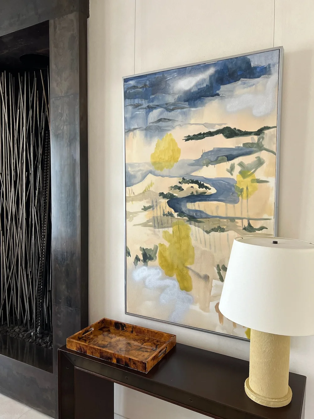 Landscape painting installed above a dark wood console