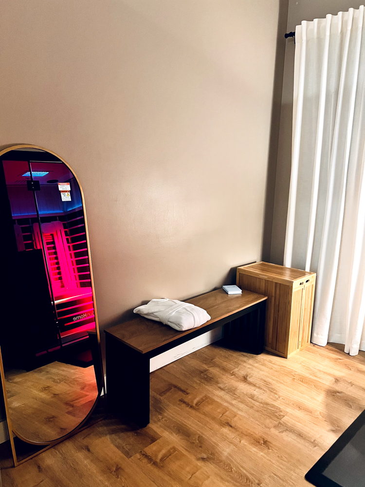 Infrared sauna glowing red beside a relaxation bench at Recoupia in Lynnwood