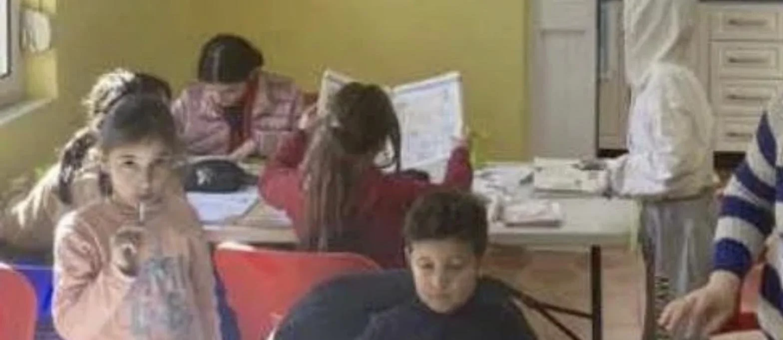 Children following along with workbooks as a Tek Ura tutor teaches at the Tirana homework club