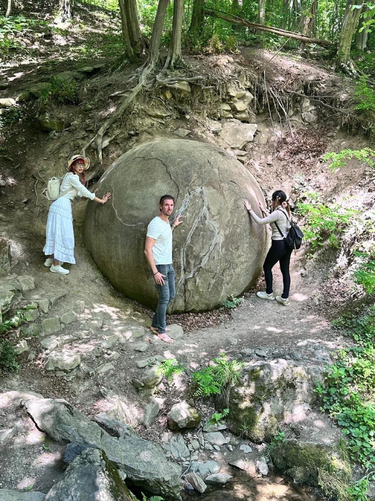 Visitors beside an entire giant stone sphere