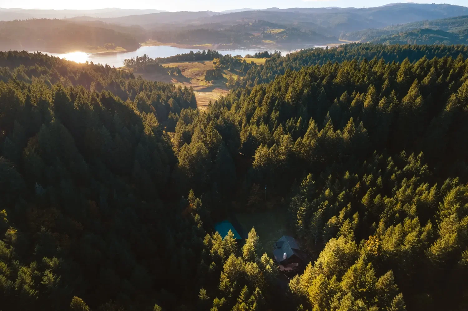 Aerial view of FernLove's forested acreage above Hagg Lake at golden hour