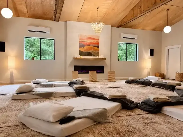 A light-filled indoor space at Fernlove set up with mats, pillows and blankets for a group session