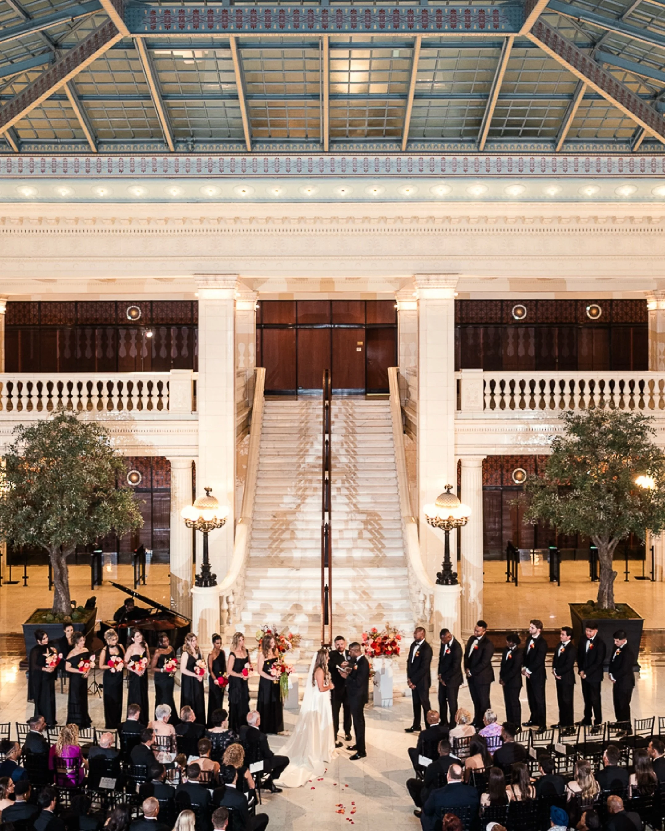 Taylor and Emery’s wedding ceremony framed by flowers beneath The Exchange skylight in Chicago