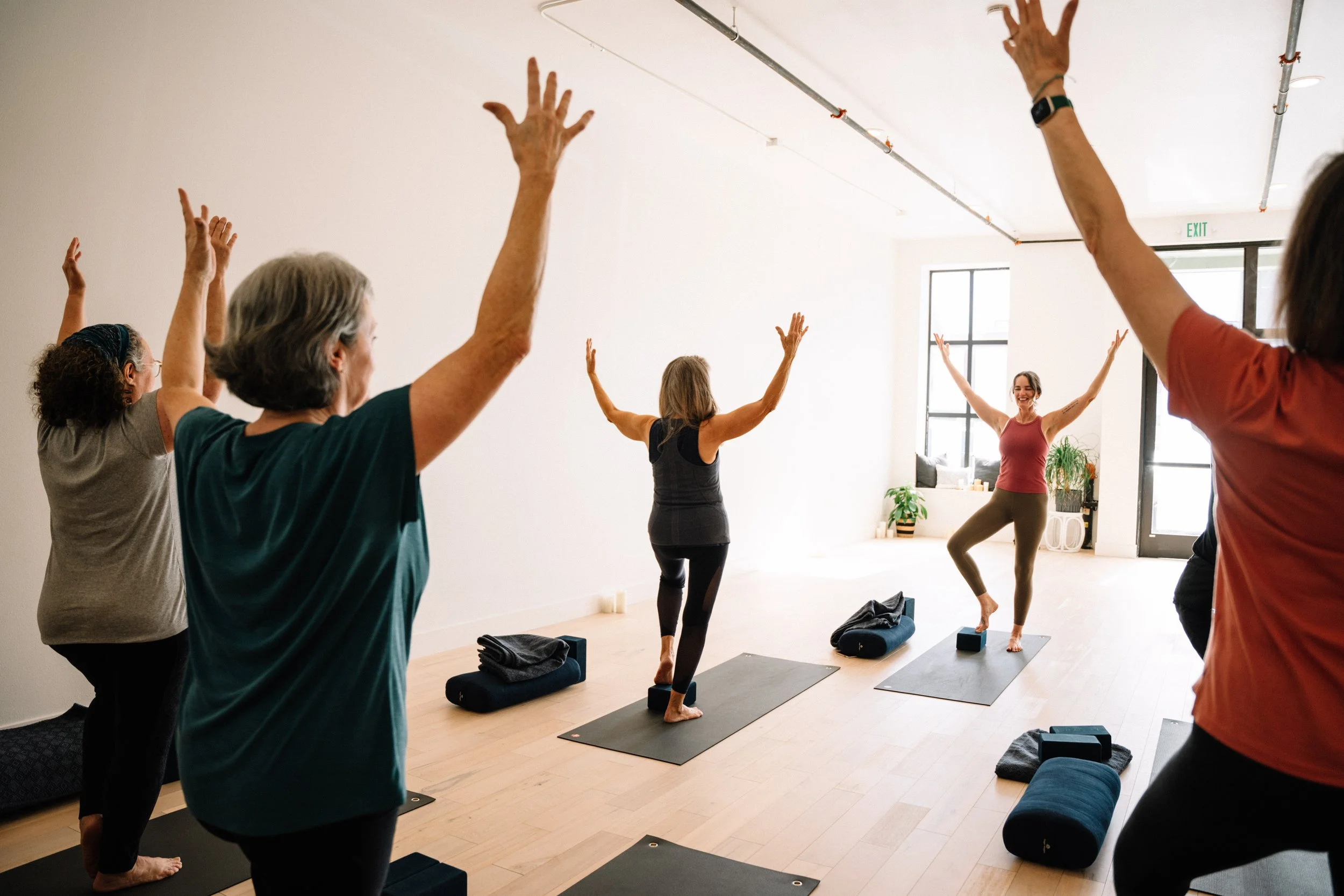 Older students reaching their arms overhead together in a gentle yoga class