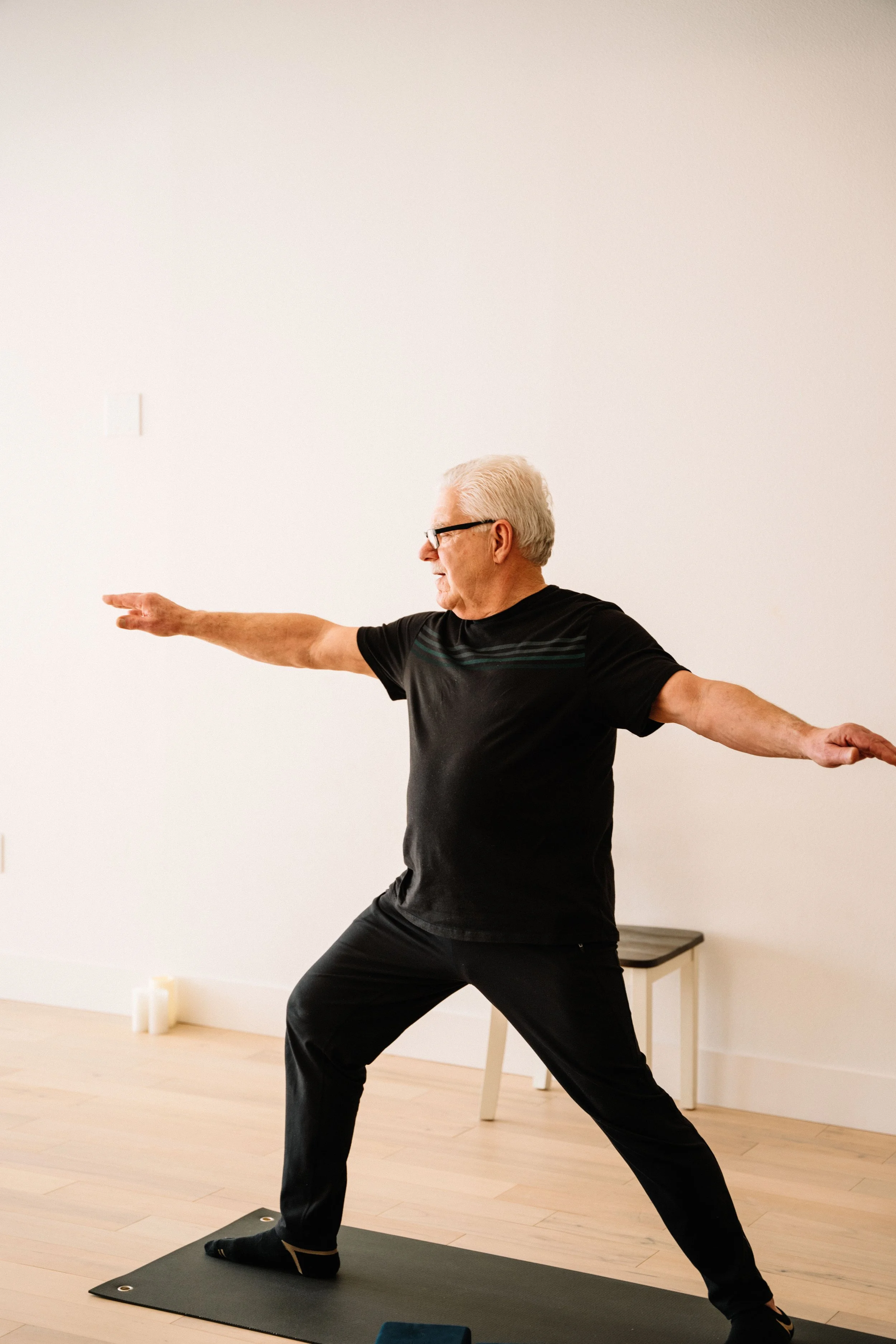 A student holding warrior two with both arms extended in a warm slow flow class