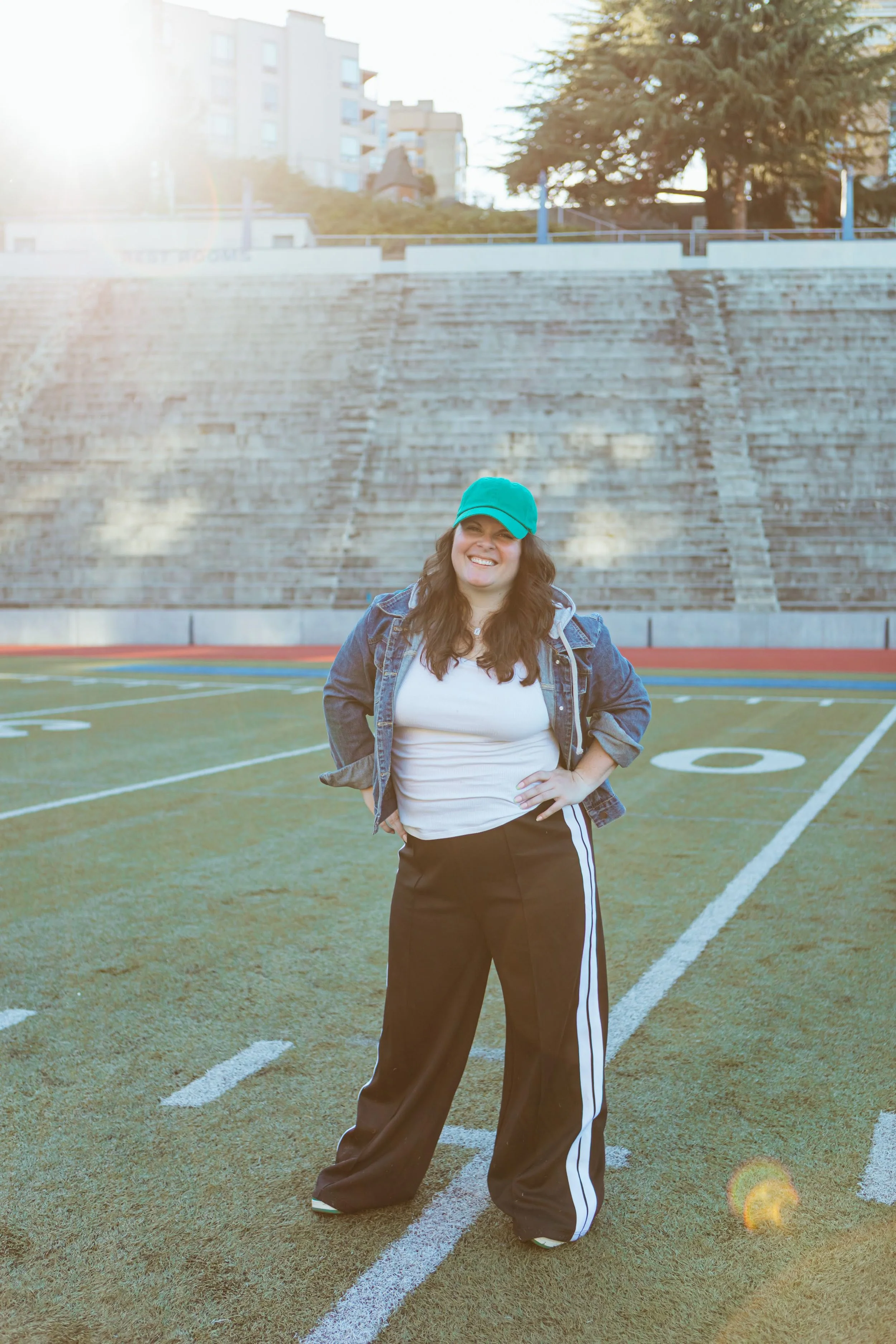 Ellyn on the field pointing at the camera, soccer ball under her arm