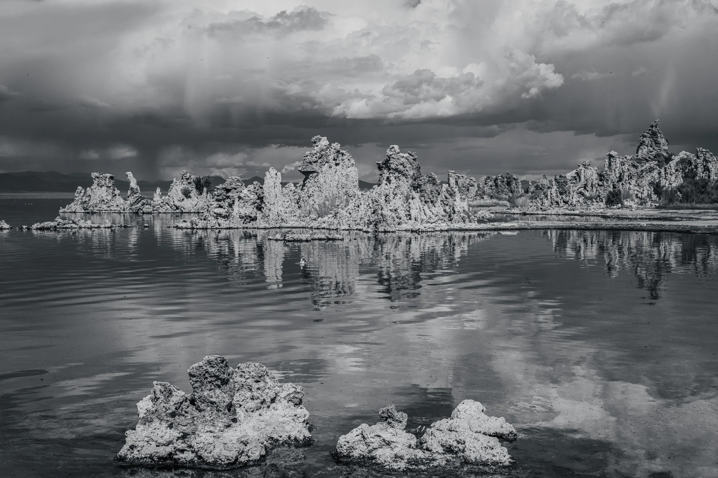 Stone formations mirrored in a still lake beneath a gathering sky