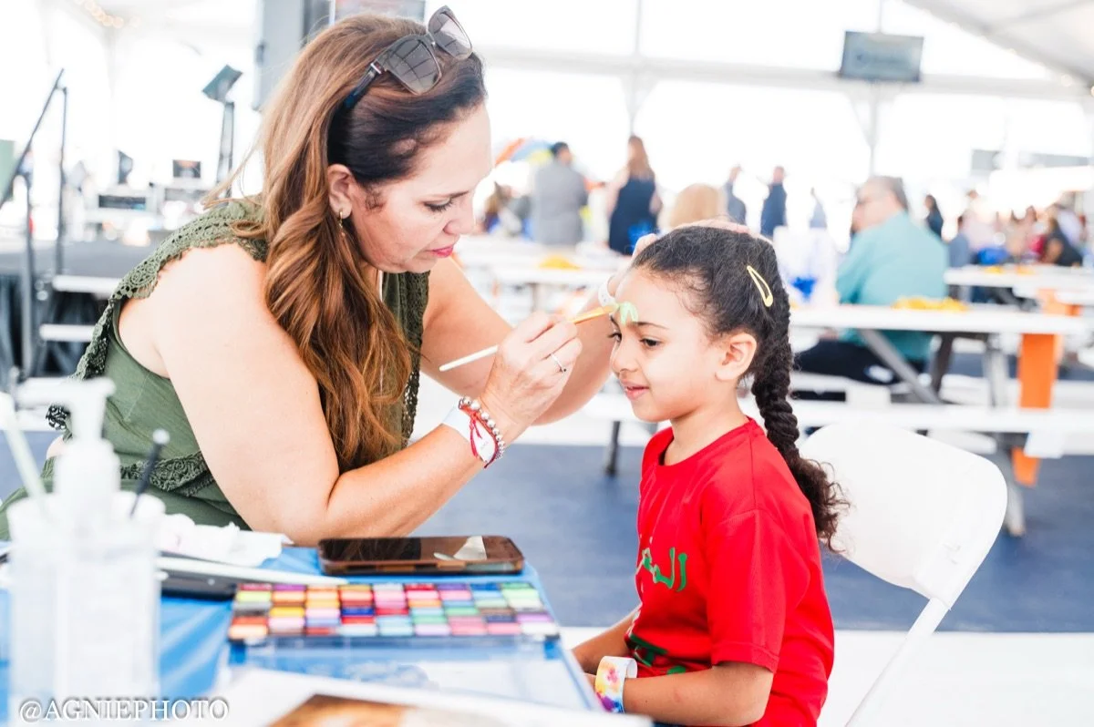 A child gets her face painted at the family celebration on the dock.