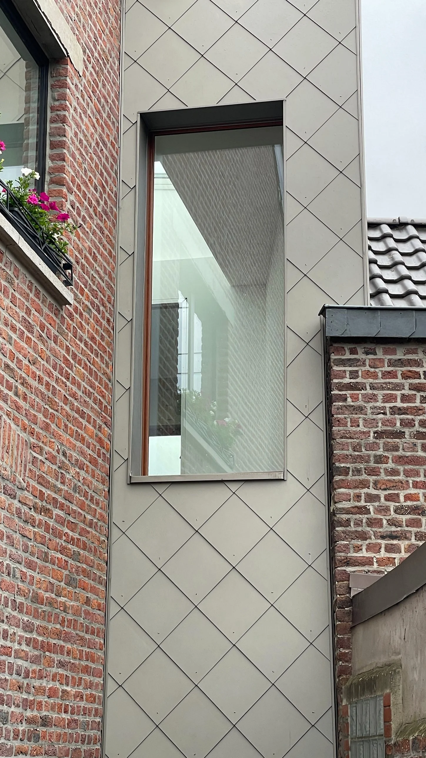 La façade en bardage losangé et sa baie verticale
