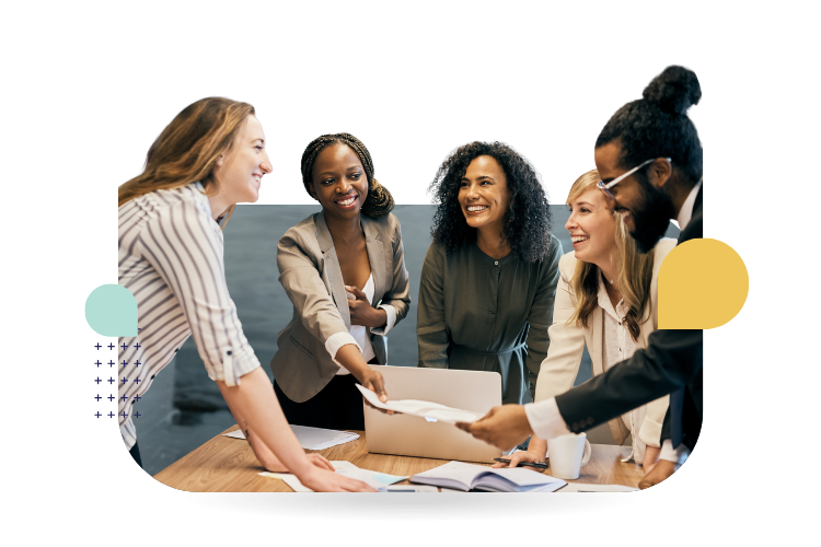 Five colleagues collaborate around a laptop and documents at a table, smiling and engaged in a workplace discussion.