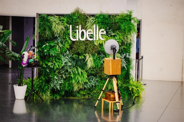 Houten photobooth voor een groene plantenwand met Libelle-logo