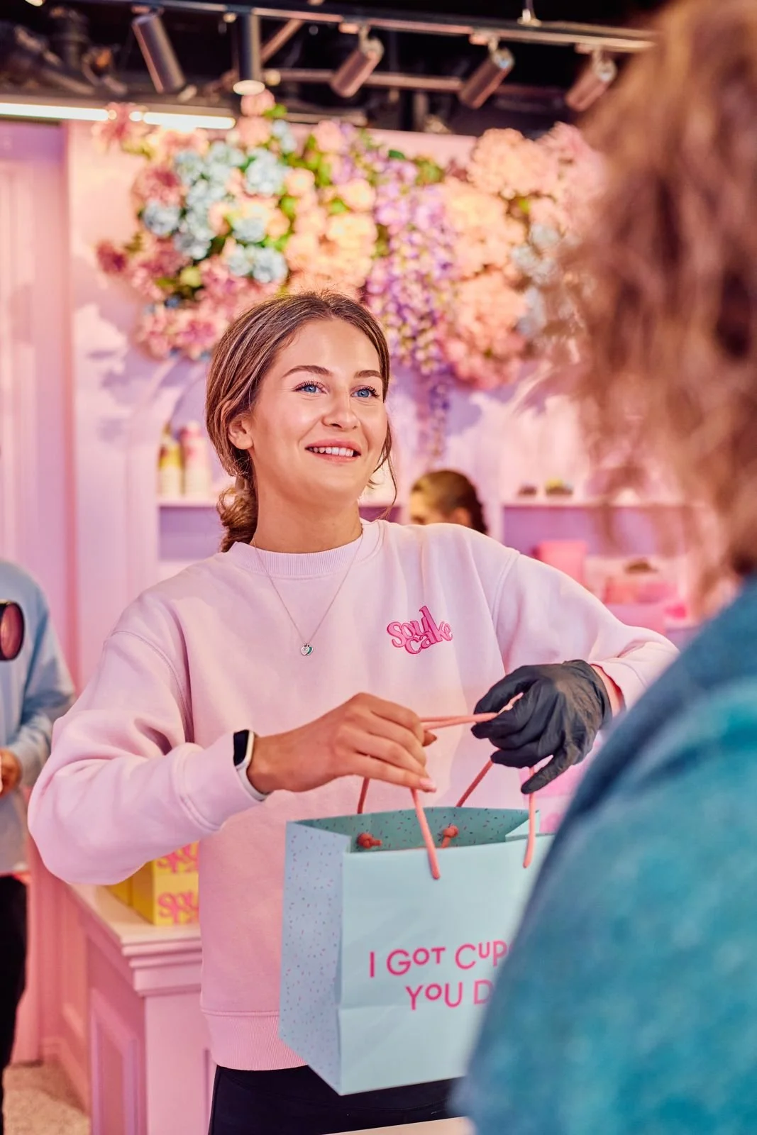 Ansatt i rosa Soulcake-genser gir en kunde en pose over disken