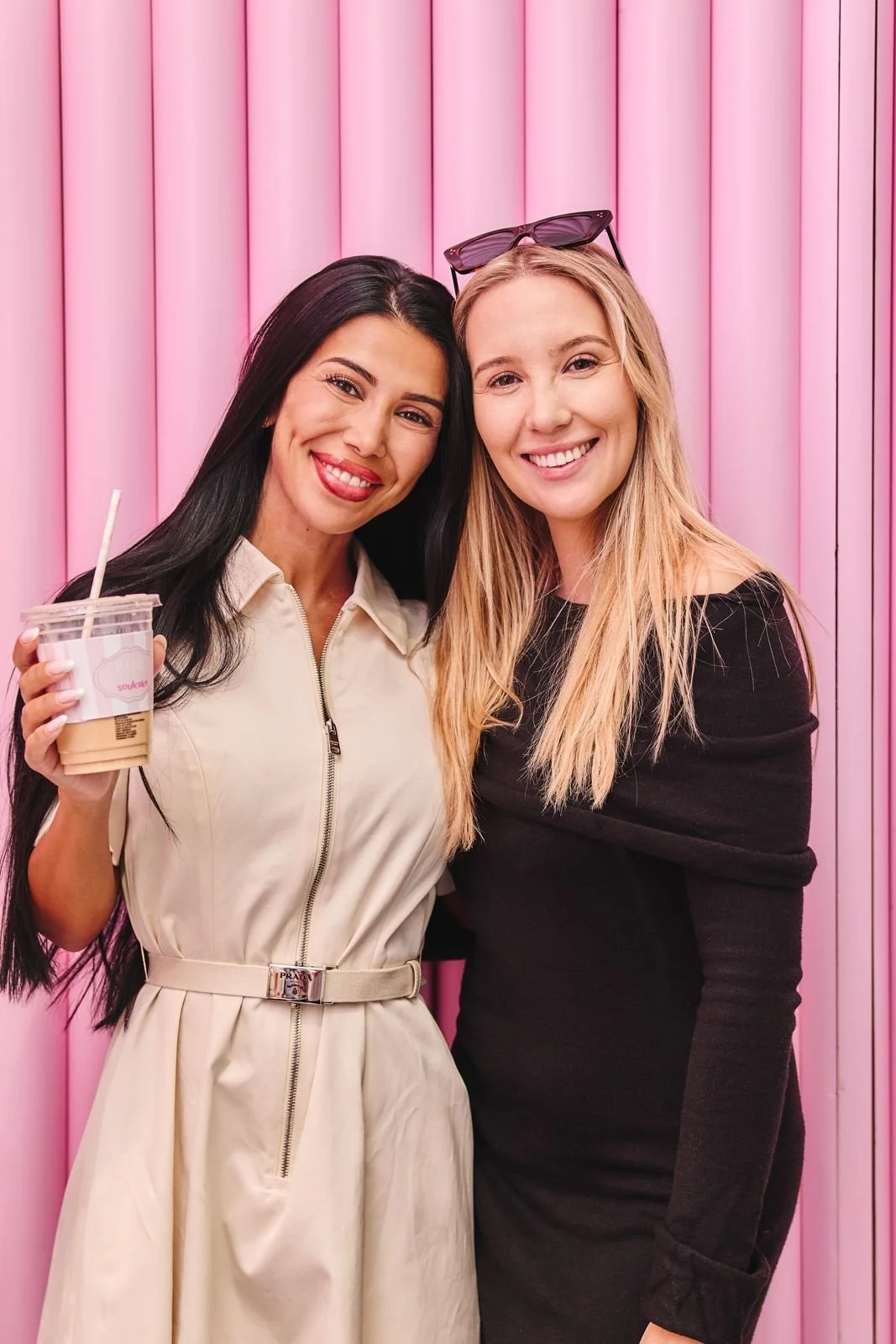 To kvinner foran rosa vegg med iskaffe fra Ivorie x Soulcake