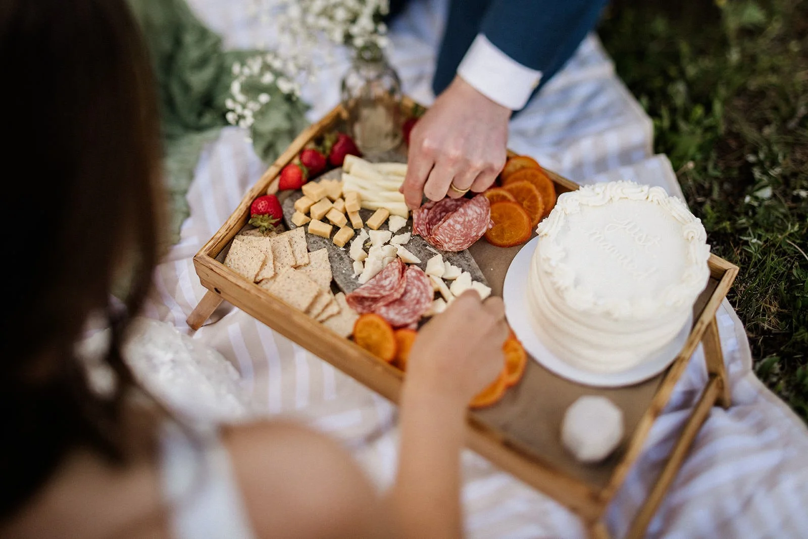 A couple picks at a charcuterie board they bring to their elopement