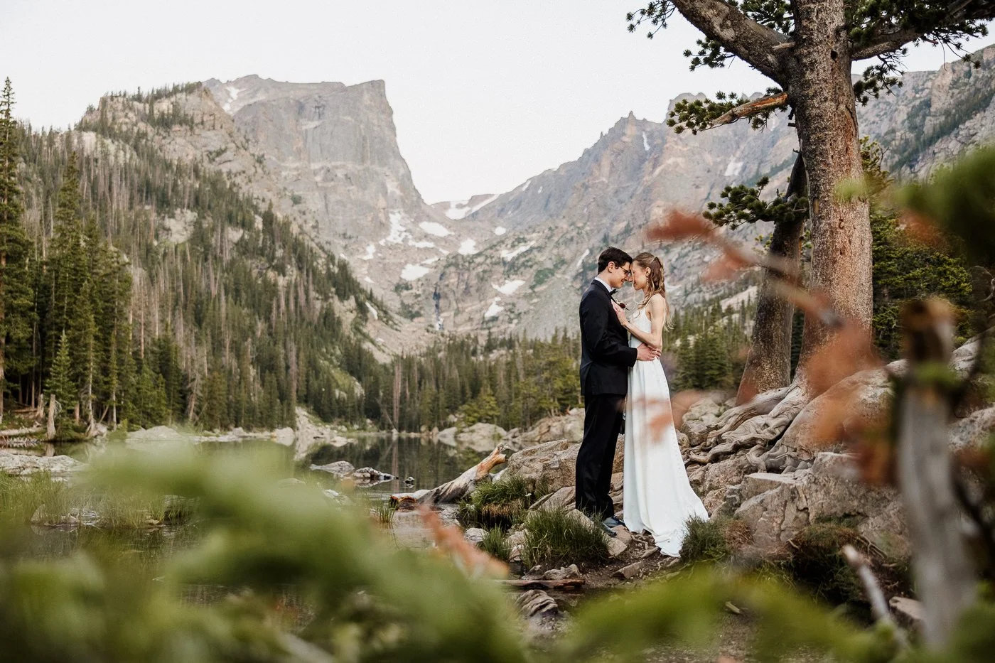 A couple at an alpine lake with an empty shoreline behind them