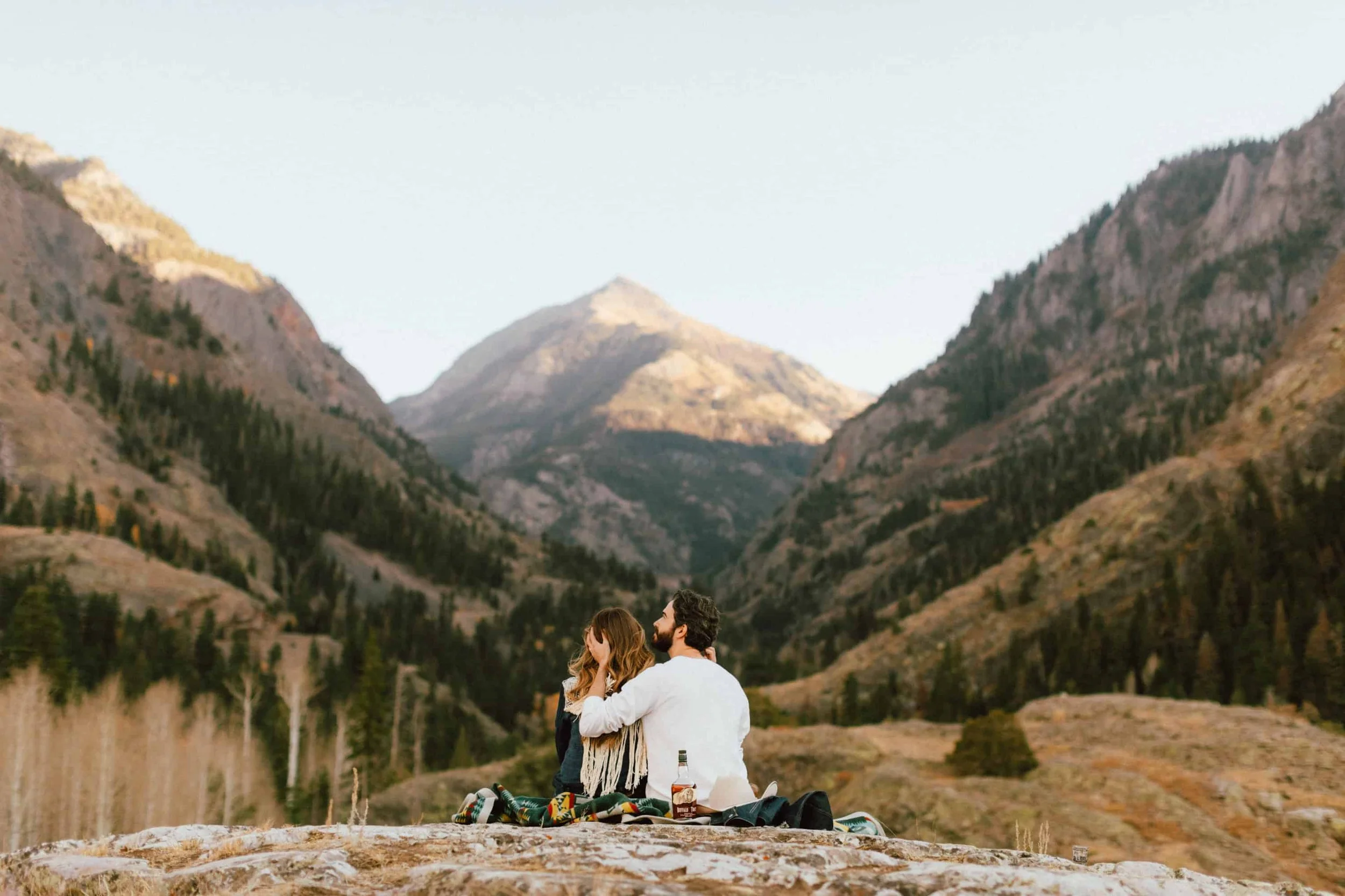 A couple standing together on an overlook above Ouray, Colorado, with jagged peaks behind them