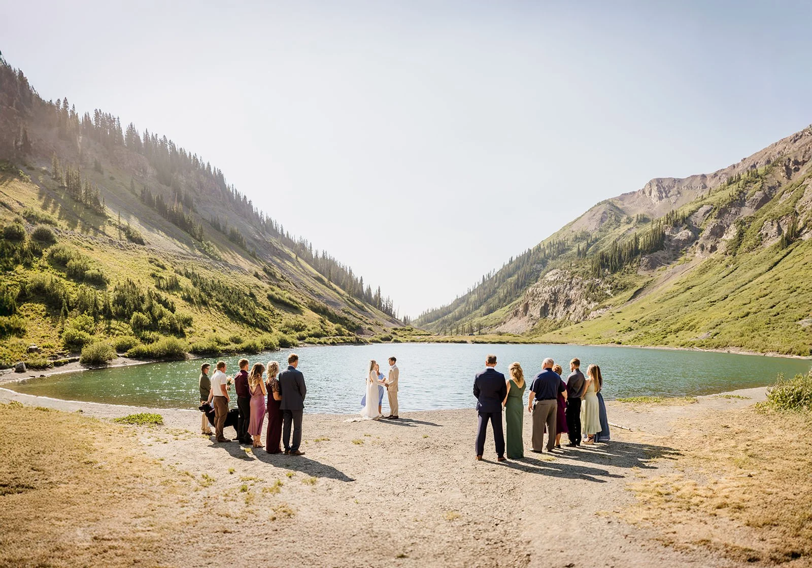 A couple and a small group of guests in front of a lake in midday light