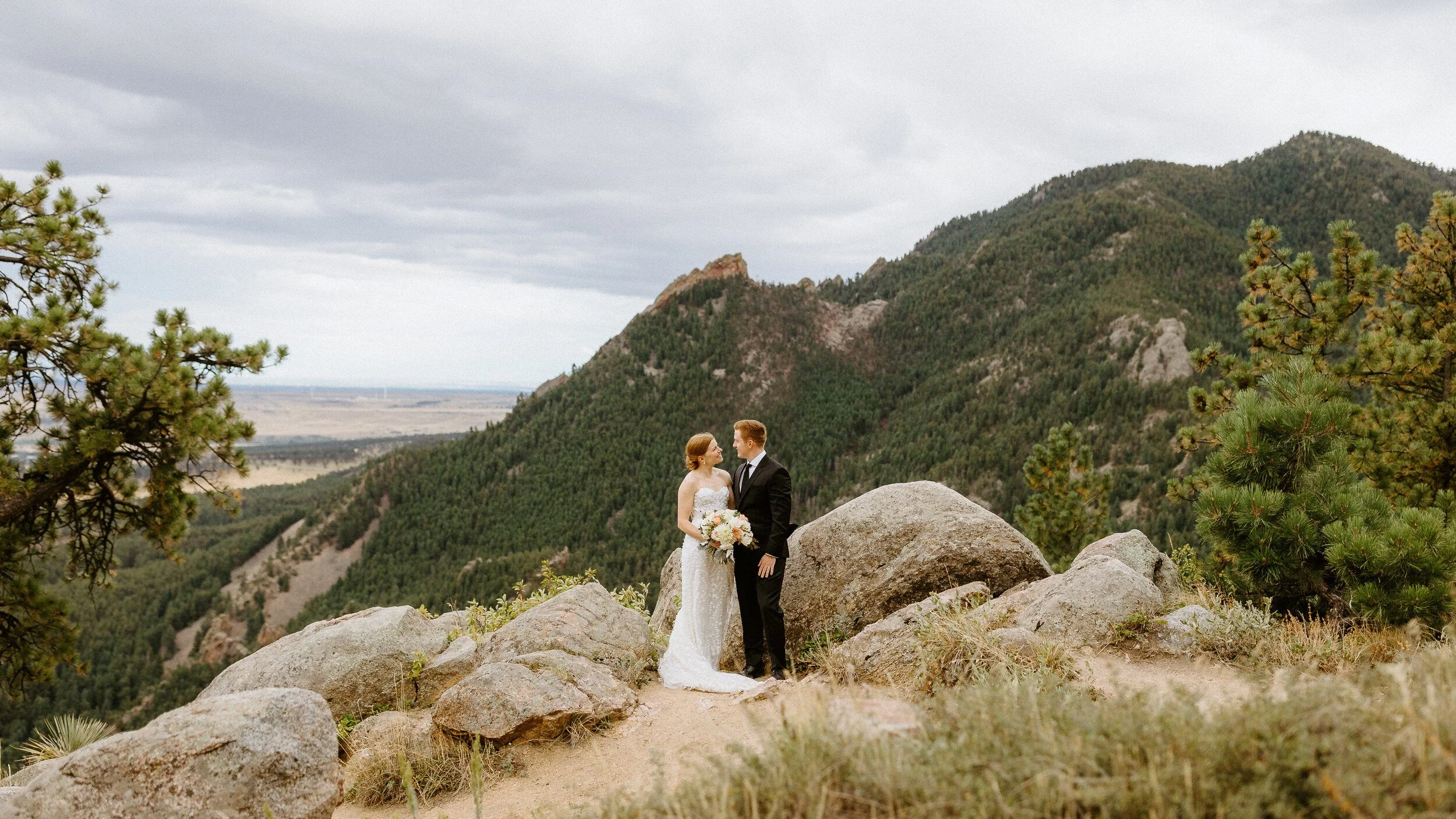 A couple in wedding clothes stands at Sunrise Amphitheater in Boulder, Colorado