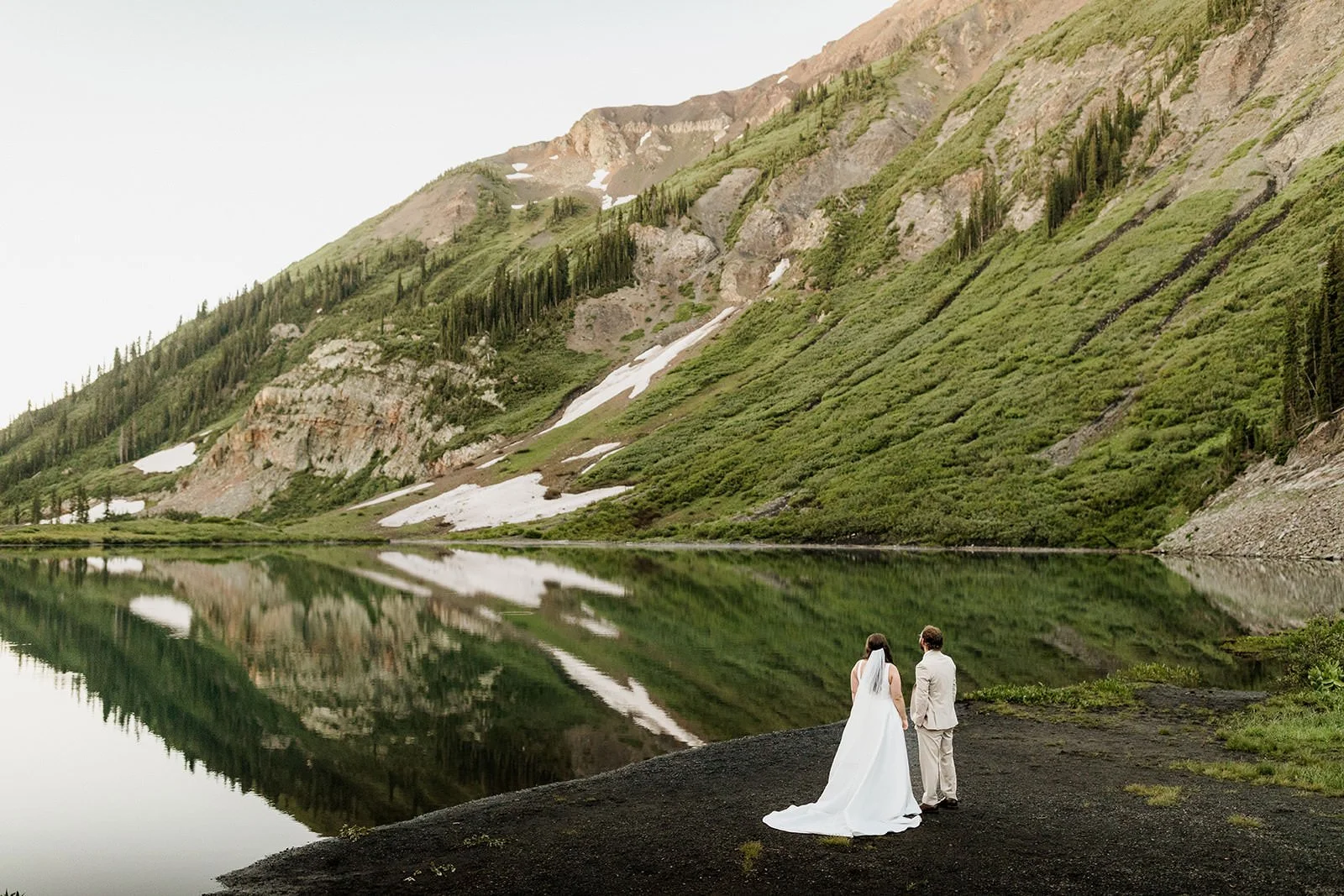 Ceremony under a floral arch on a green hillside