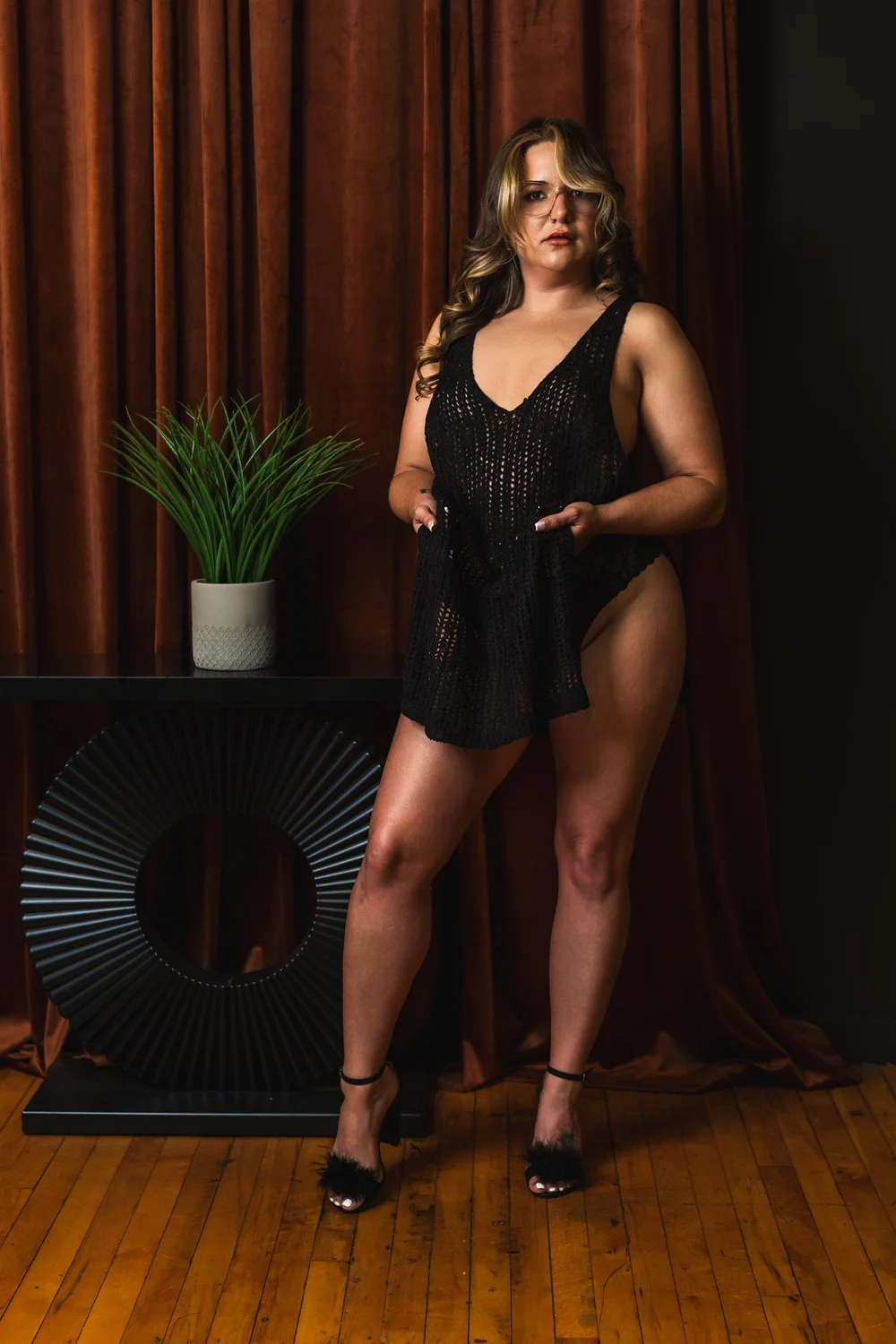 Full-length portrait of Alicia in a black dress against bronze curtains