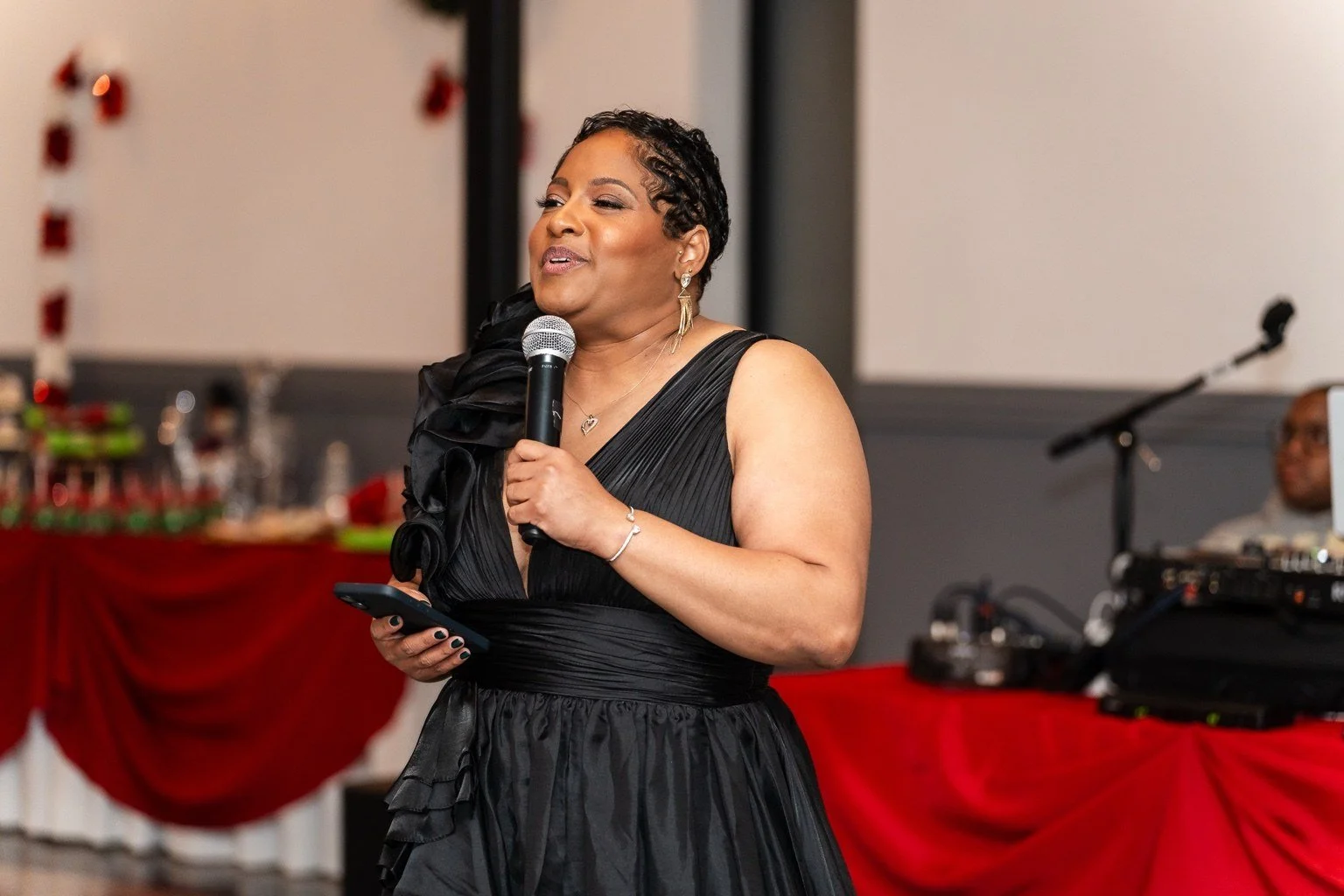 Angelia speaking into a microphone at the Kidz Stuff holiday party