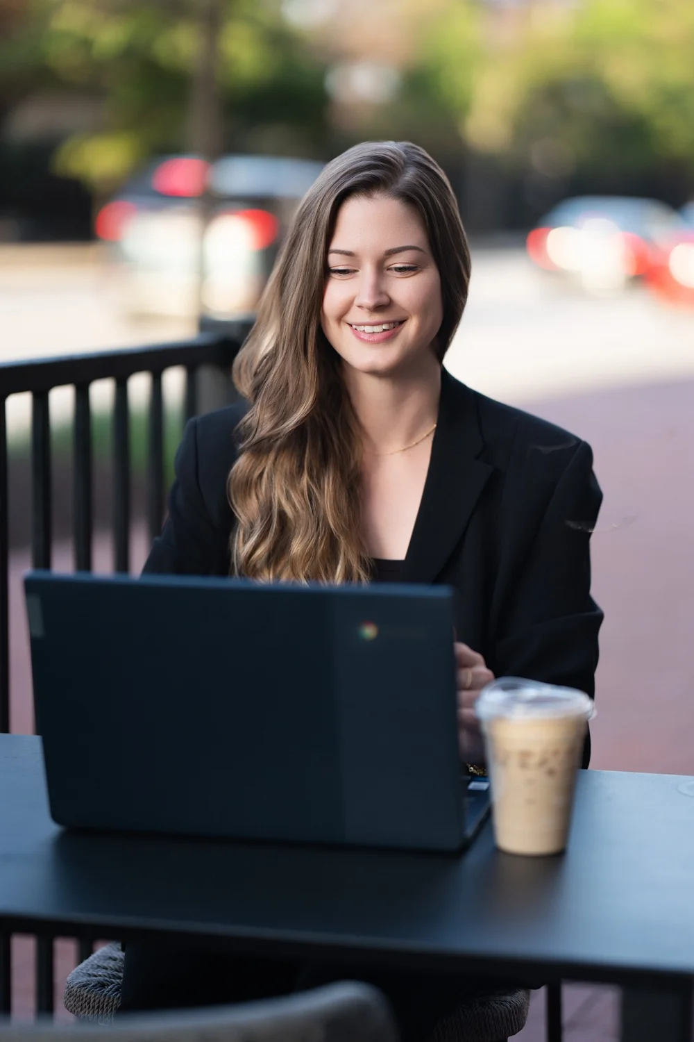 Sam Rodgers working at a laptop on an outdoor café patio in Baltimore