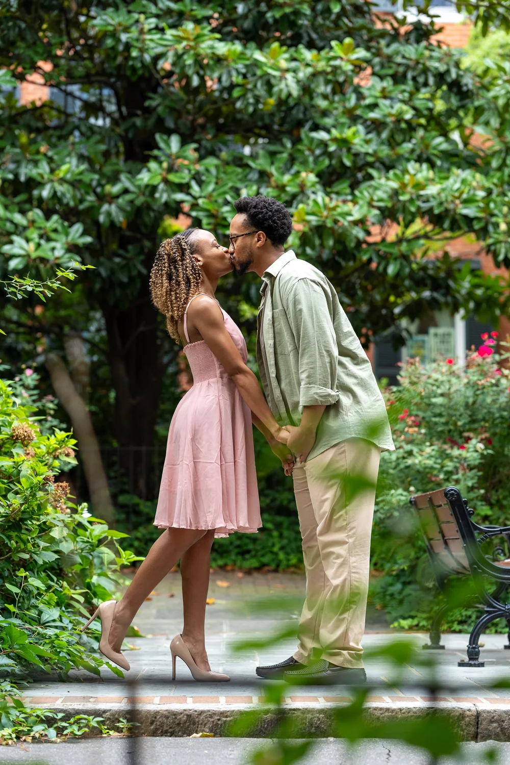 Brook and Morgan sharing a kiss among garden greenery during their Baltimore engagement session