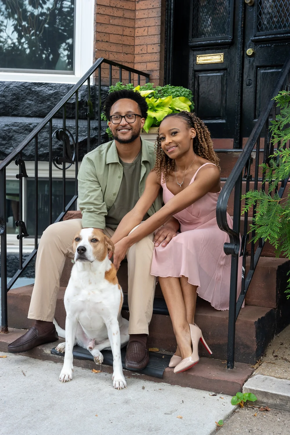 Brook and Morgan smiling with their dog on brownstone steps