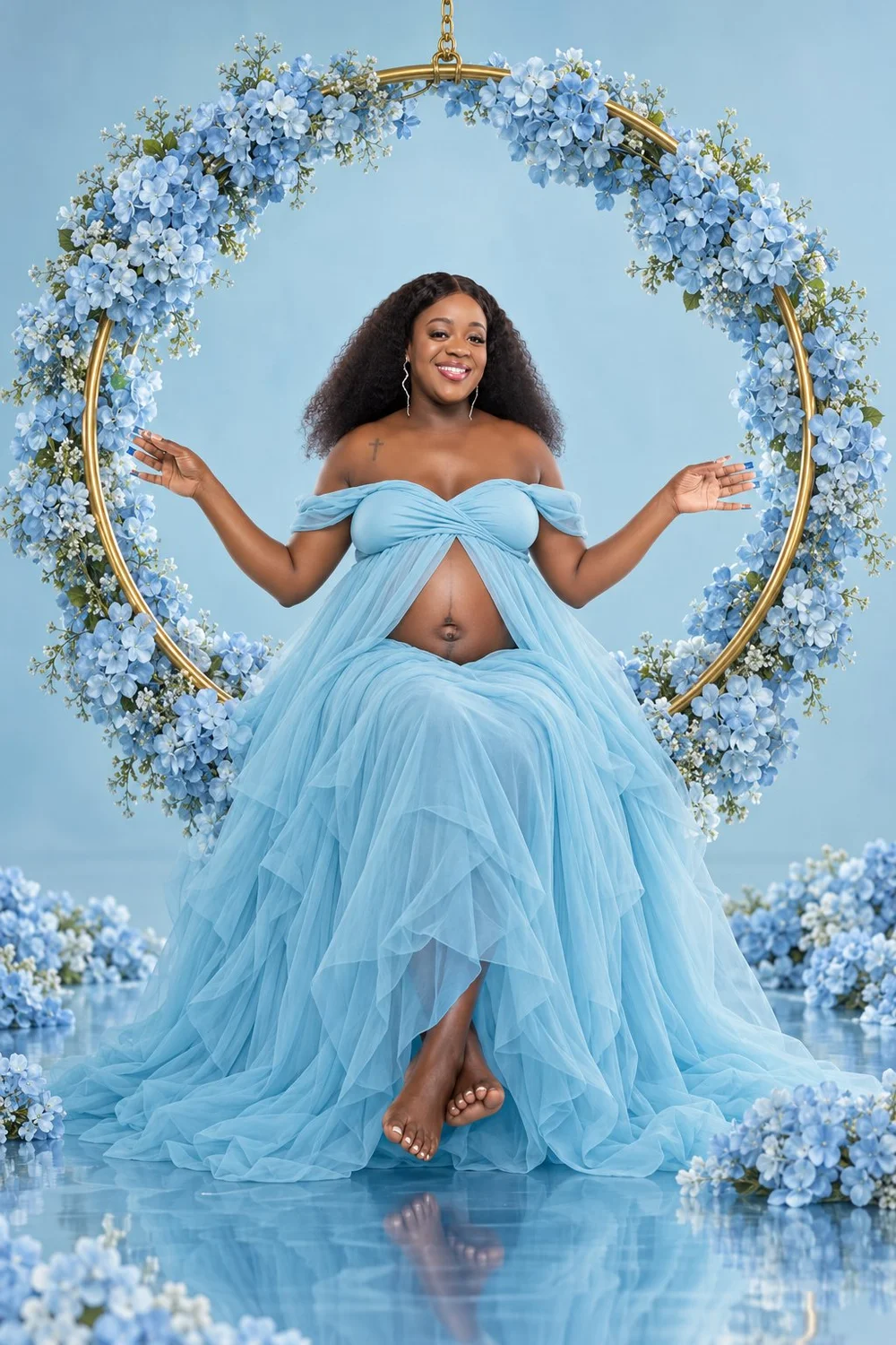 Front-facing maternity portrait of Capria in a blue gown on a floral hoop swing
