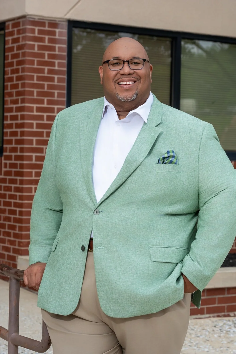 Dr. Michael Dorsey smiling in a mint green blazer beside a brick building in Baltimore