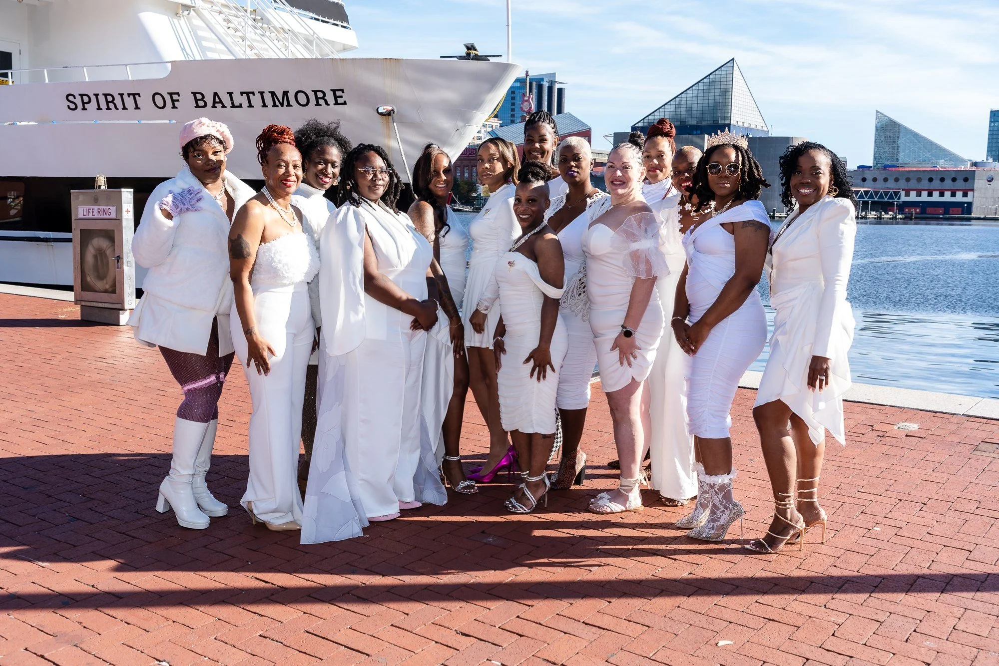 Guests in white outfits posing together beside the Spirit of Baltimore