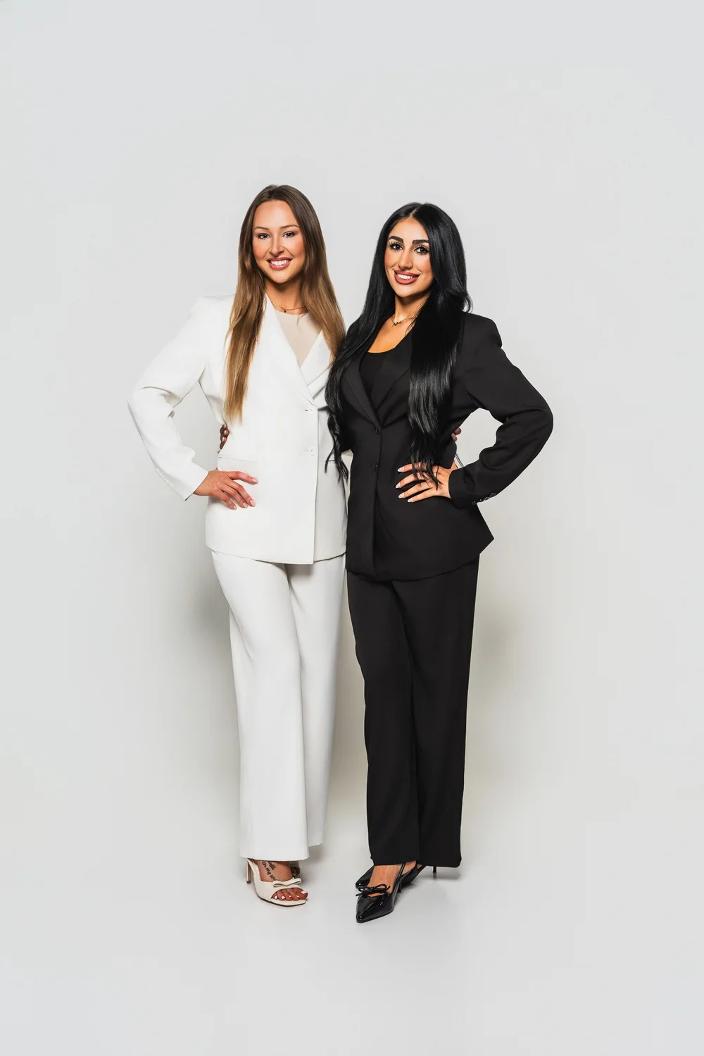 Mimi and Kaelie of DuoGlo Esthetics in tailored black and white suits