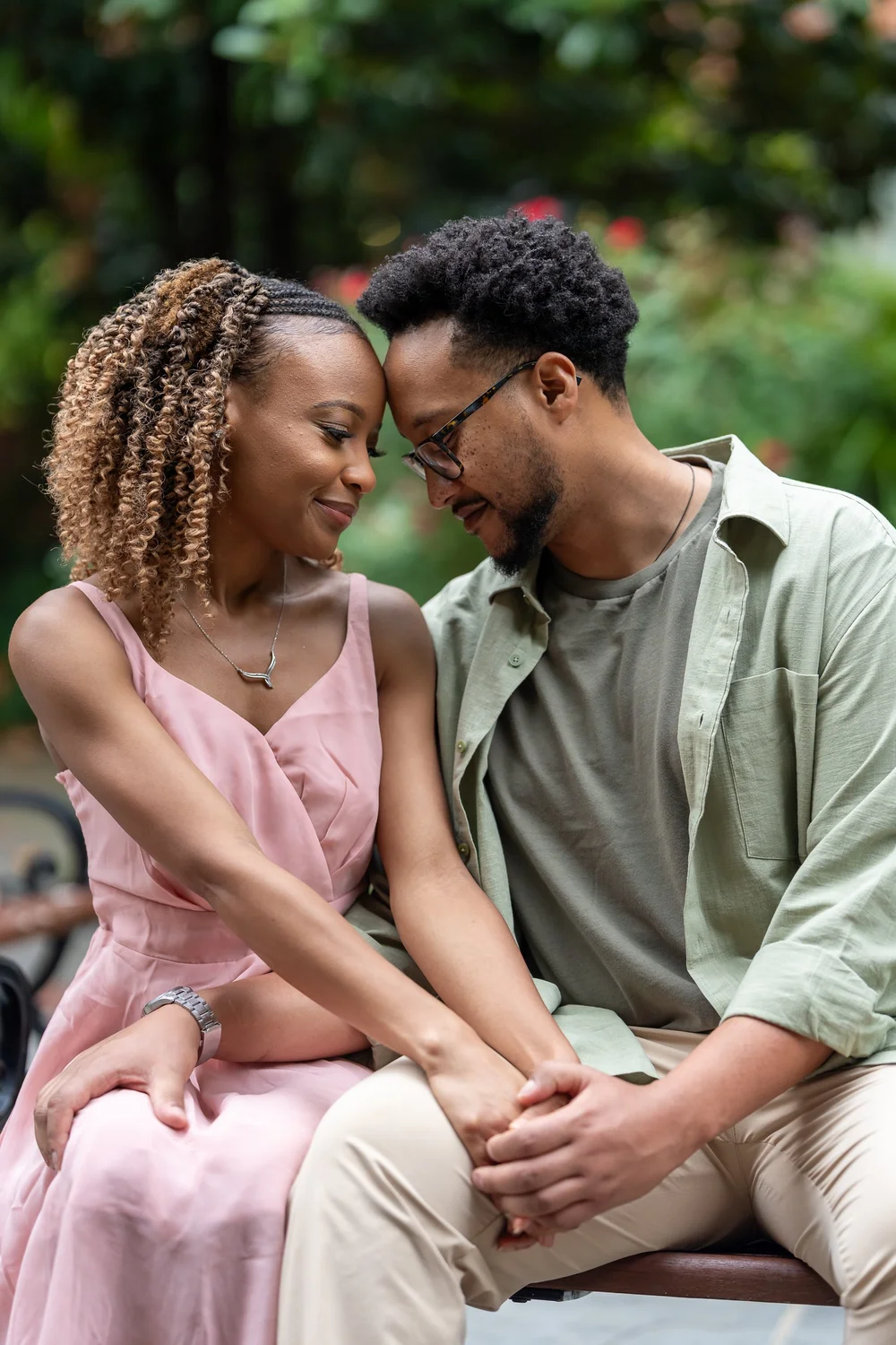 Brook and Morgan touching foreheads and holding hands on a garden bench
