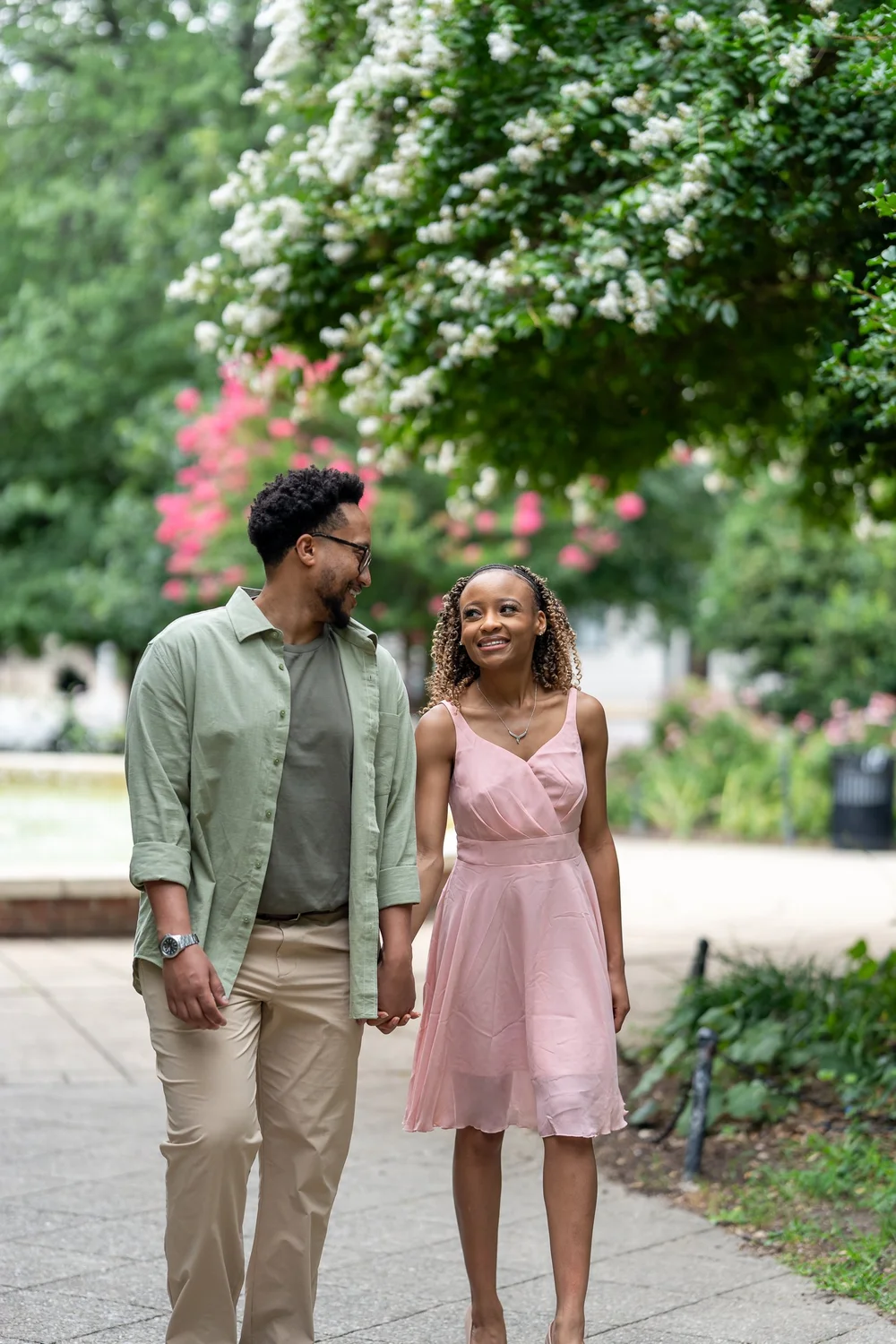 Brook and Morgan smiling at each other as they walk hand in hand beside a fountain